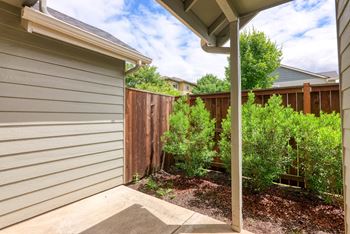 a side view of a house with a yard and a fence at Trillium Apartments, Oregon 97477